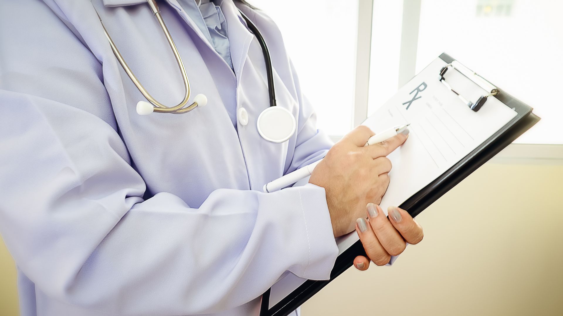 Doctor in white coat with stethoscope holding medical clipboard