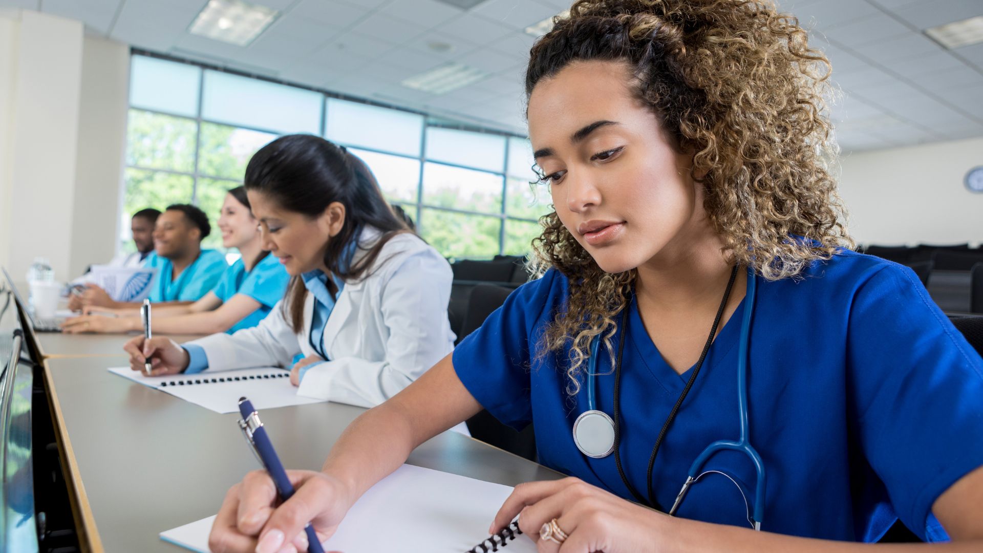Medical students taking notes during class in modern classroom
