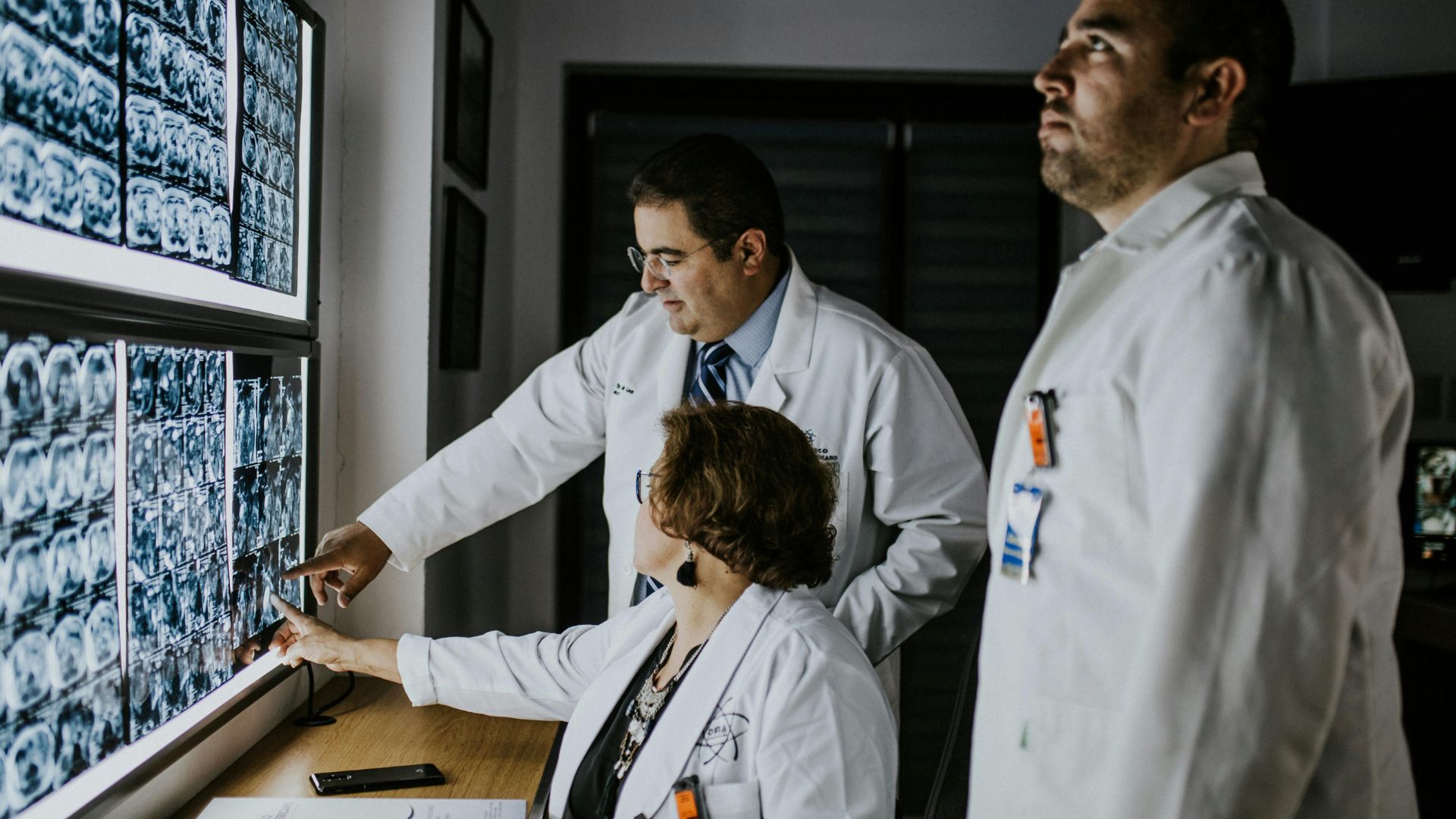Medical professionals reviewing brain scans on multiple computer monitors