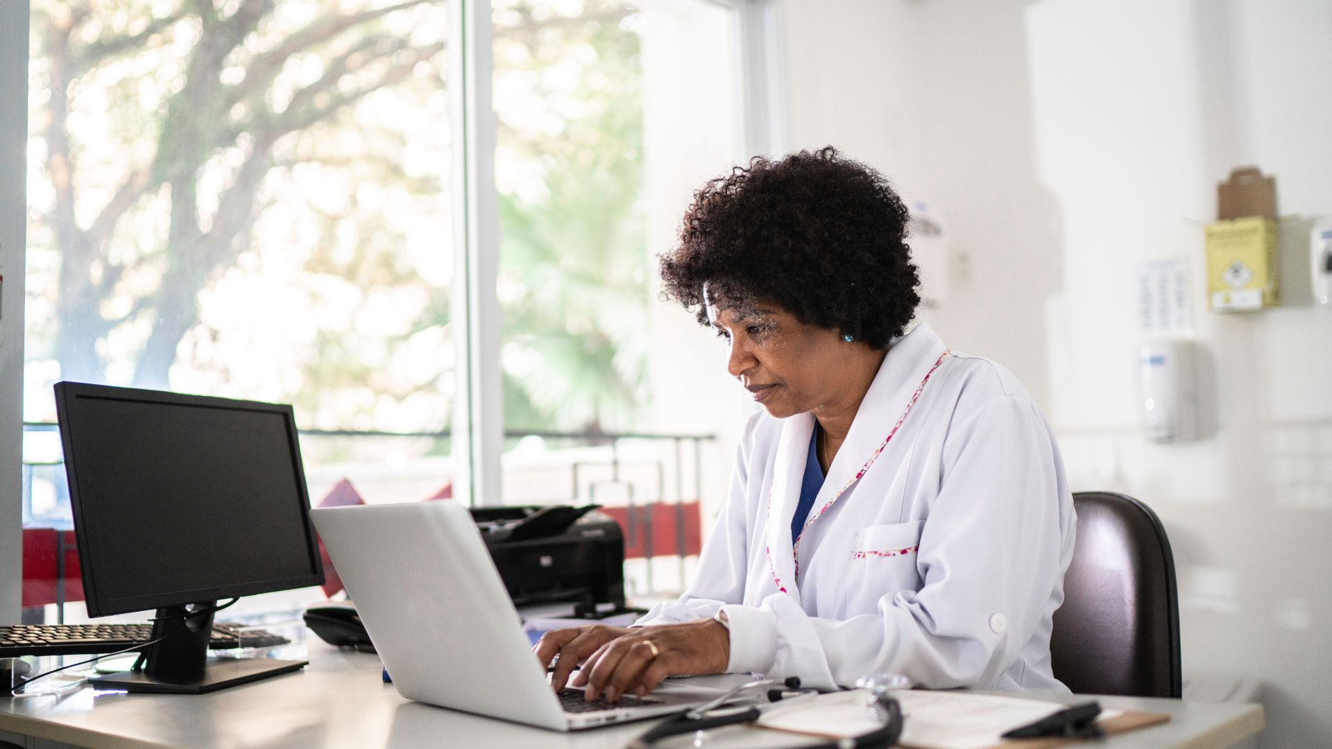 Medical professional working on laptop in bright office with window